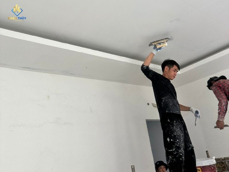 Thợ Nhân Thủy dùng bàn bả trét lớp bả matit lên tường đã xử lý bề mặt