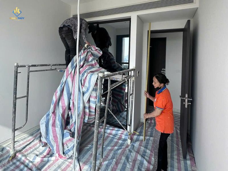 Nhóm thi công trải và bố trí bạt che chắn sàn quanh giàn giáo trong phòng