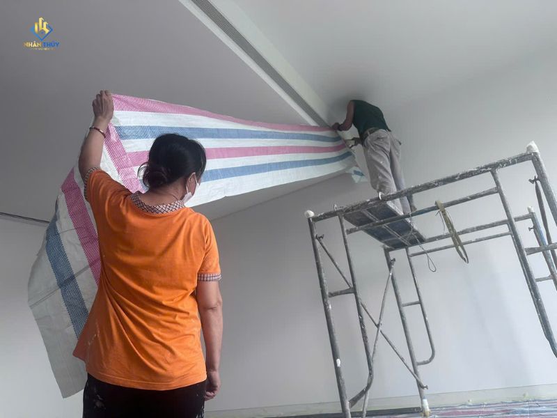 Nhân viên căng bạt che chắn khu vực trước khi sơn nhà