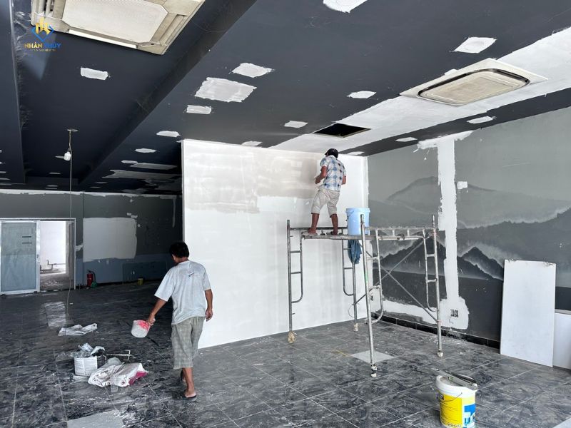 Thợ dặm vá và xử lý bề mặt tường, trần văn phòng trước khi sơn phủ