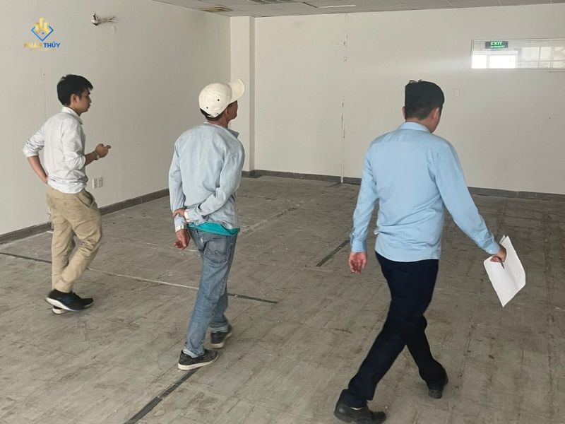 Ba người quan sát tường và trần trong một căn phòng trống