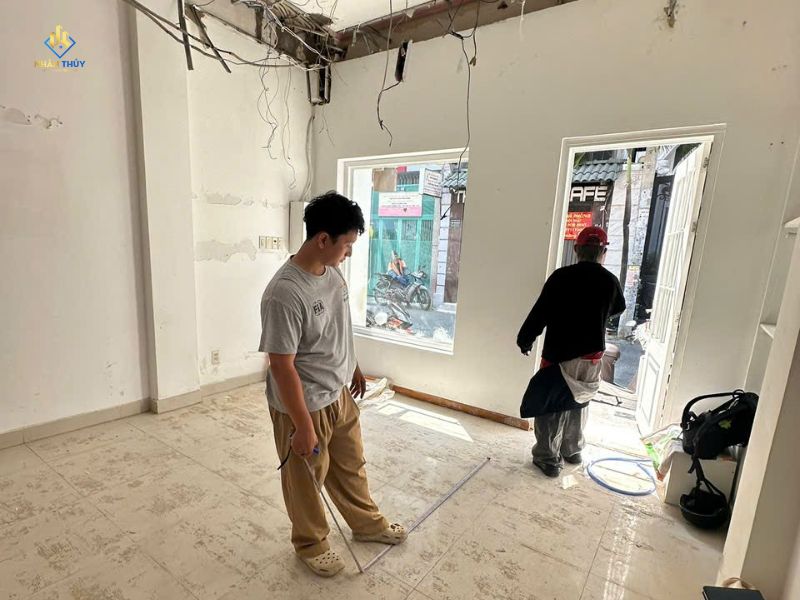 Kỹ thuật viên Nhân Thủy kiểm tra hiện trạng tường và sàn cửa hàng trước khi báo giá