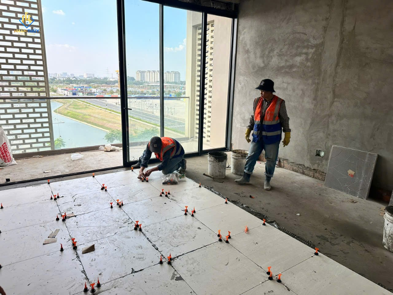Hai thợ Nhân Thủy ốp lát gạch nền bằng ke cân bằng tại nhà phố The Global City, quận 2