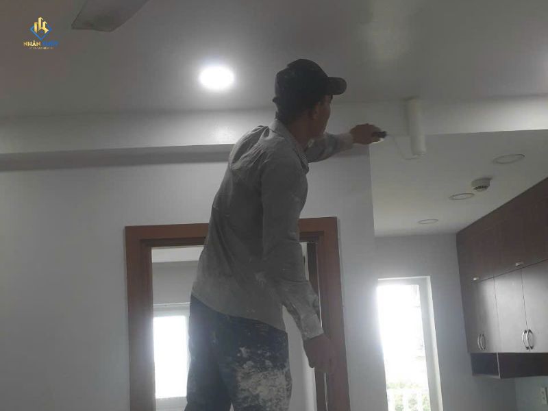 Thợ dùng con lăn nhỏ thi công dải tường sát trần trong nhà