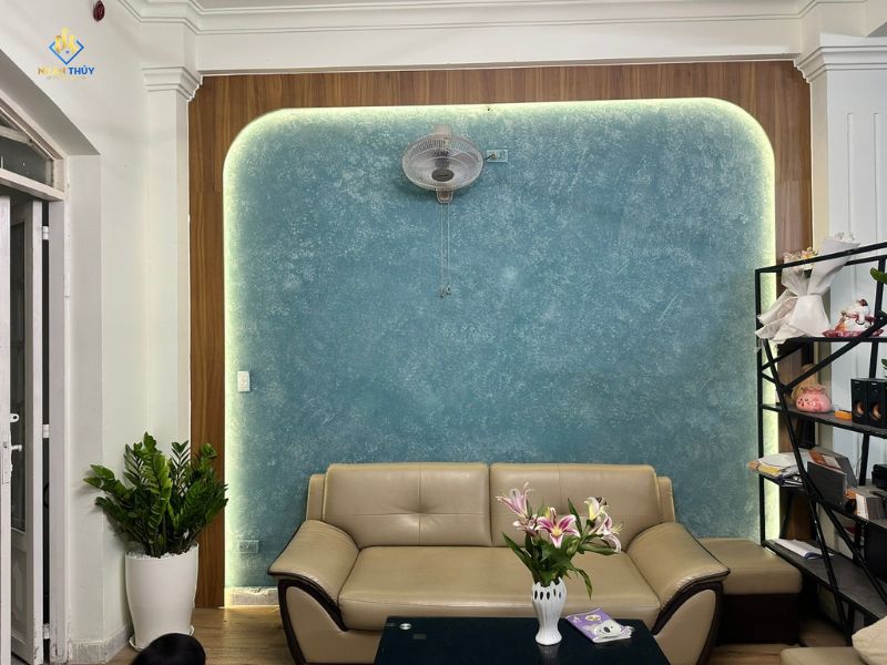 Mảng tường màu xanh có bề mặt tạo vân phía sau sofa phòng khách