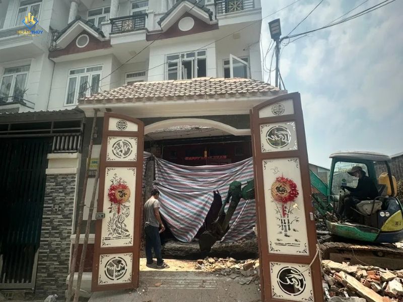 Máy đào phá dỡ mái và mặt tiền cũ của nhà phố trước khi cải tạo thành văn phòng