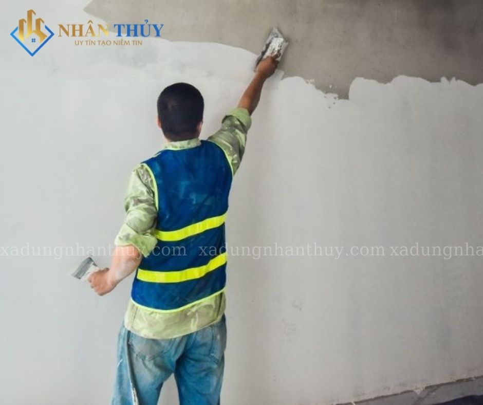 Người thợ dùng bay trét vật liệu lên mảng tường nội thất
