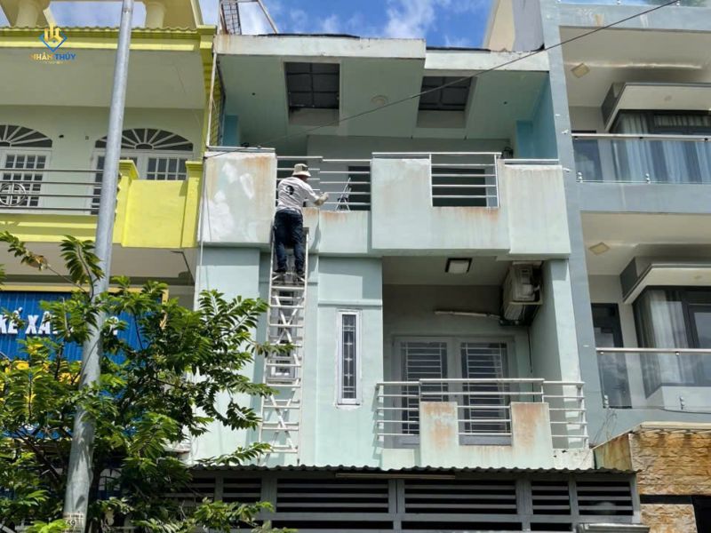 Thợ sơn mặt tiền tầng trên của nhà phố bằng thang
