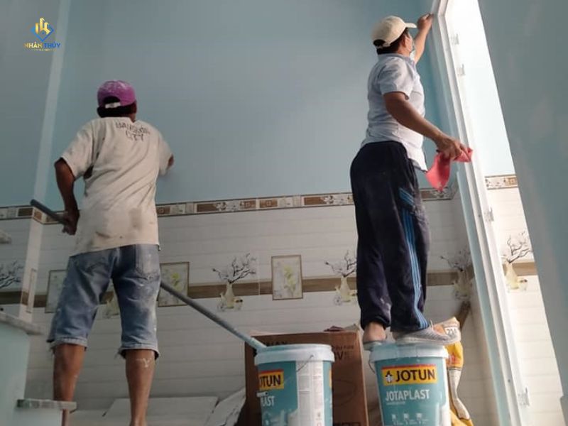 Hai người thi công phần tường và mép cửa trong phòng