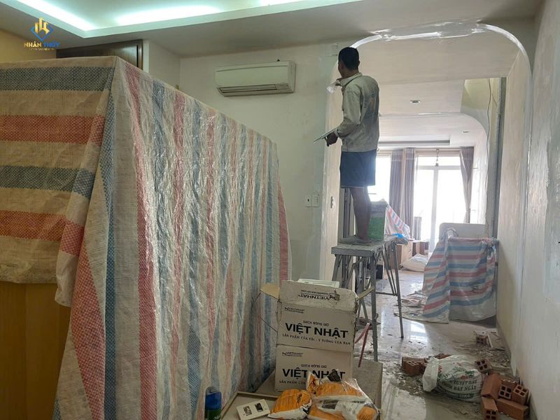 Thợ xử lý bề mặt vòm tường trong nhà, đồ đạc được che phủ