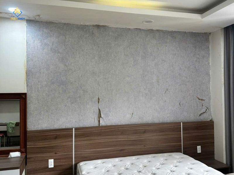 Mảng tường đầu giường nhà chị Trinh trước thi công, có lớp hoàn thiện bong nứt