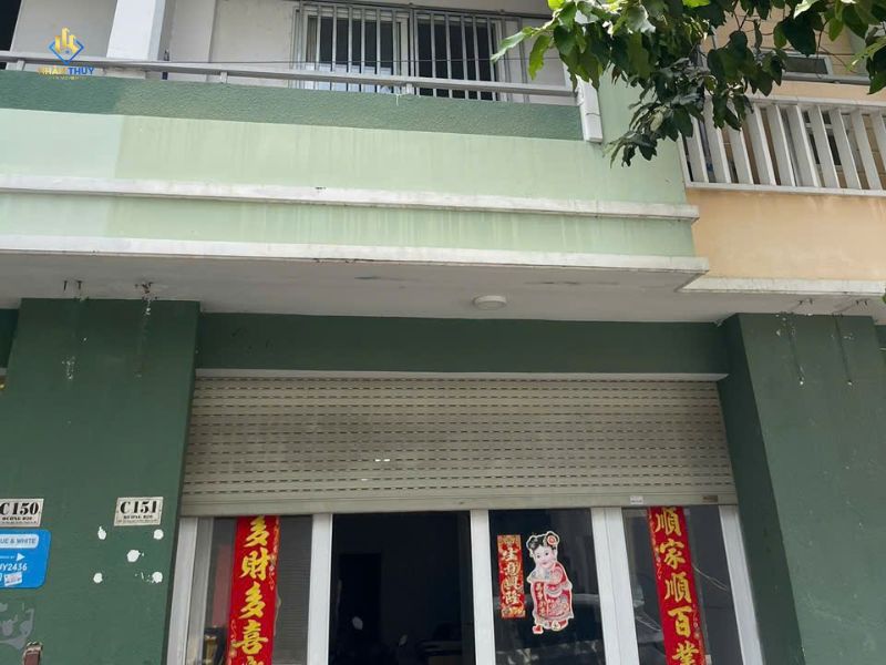 Mặt tiền nhà sơn màu xanh với ban công và cửa cuốn