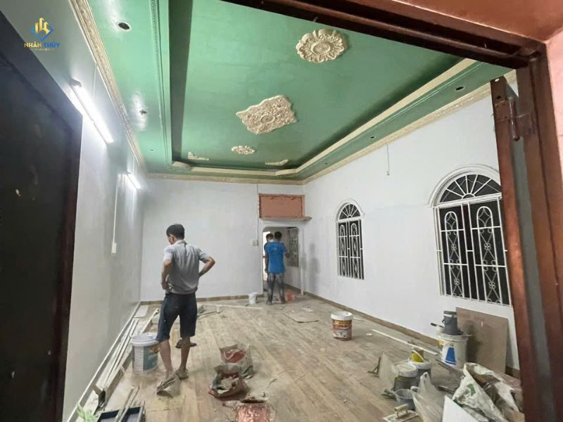 Hai thợ thi công sơn tường bên trong một căn nhà cũ