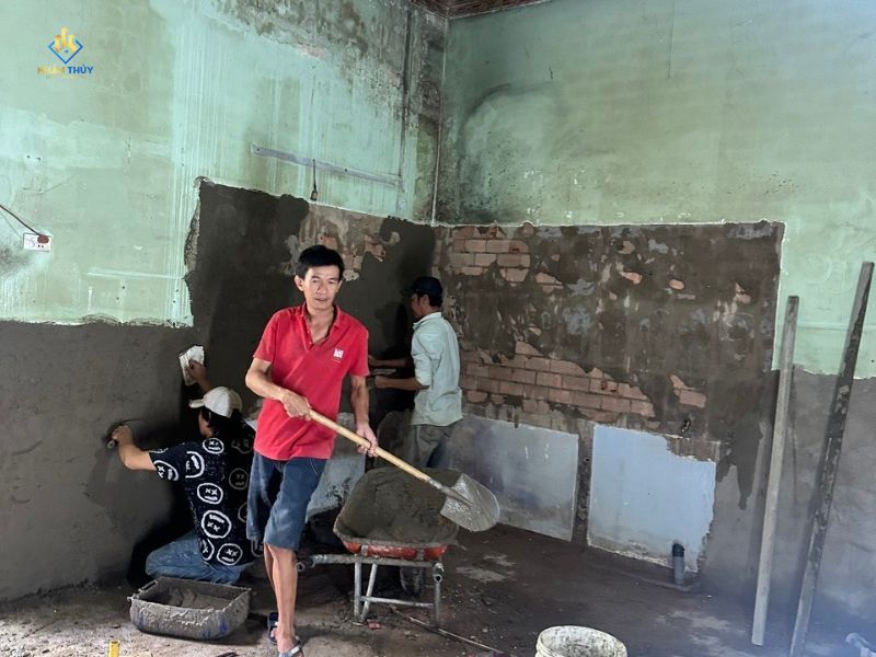 Thợ bóc lớp vữa bong trên tường nhà cấp 4 trước khi hoàn thiện